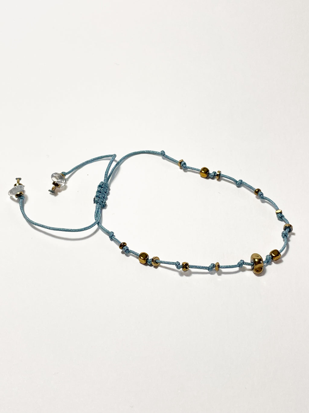 bracelet fin en hematite dorée, noeud coulissant bleu clair 