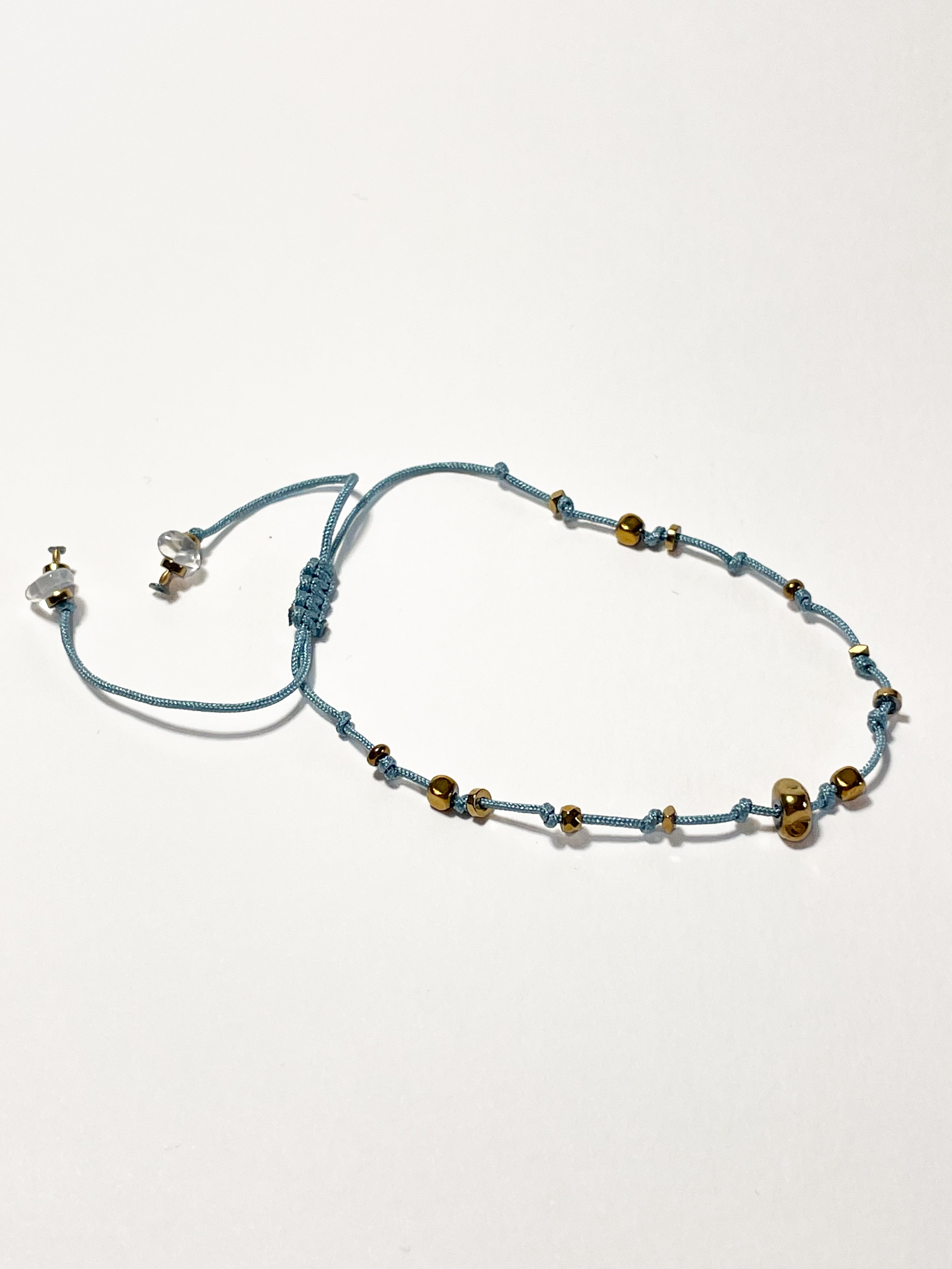 bracelet fin en hematite dorée, noeud coulissant bleu clair 